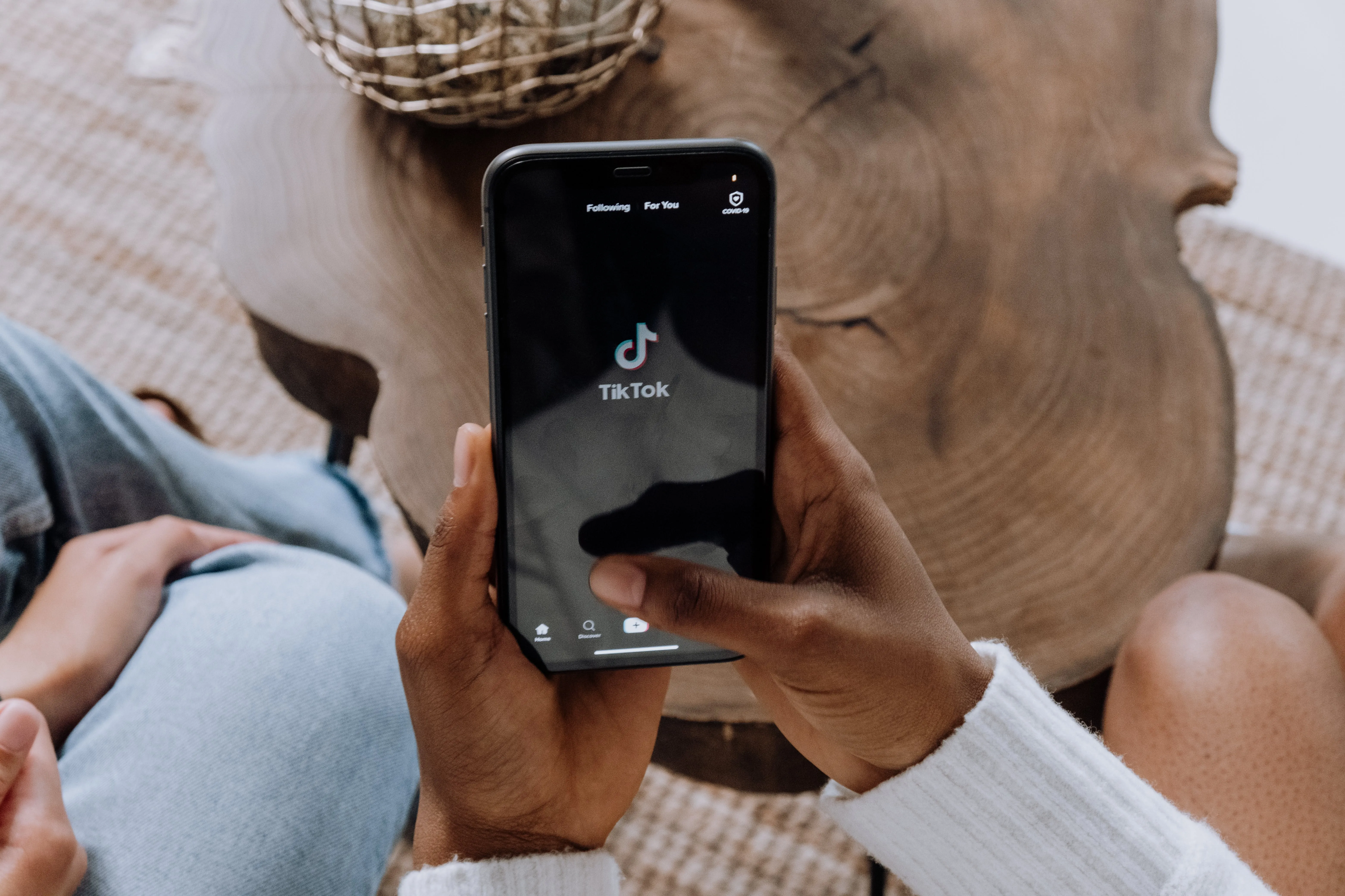 Hands holding a phone displaying the TikTok app